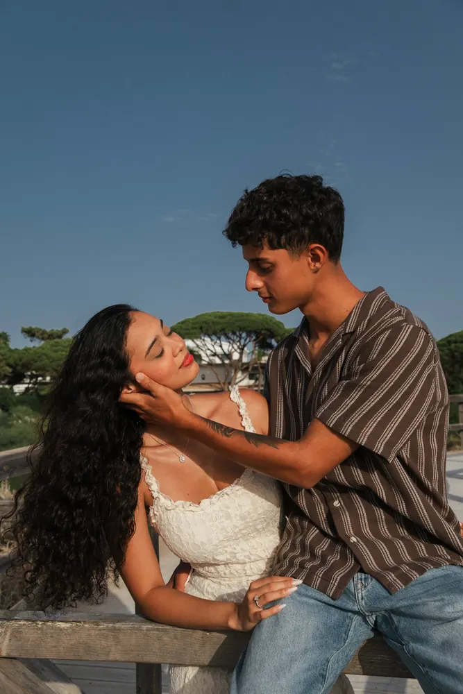 Casal abraçado num passadiço de madeira sobre as dunas do Algarve