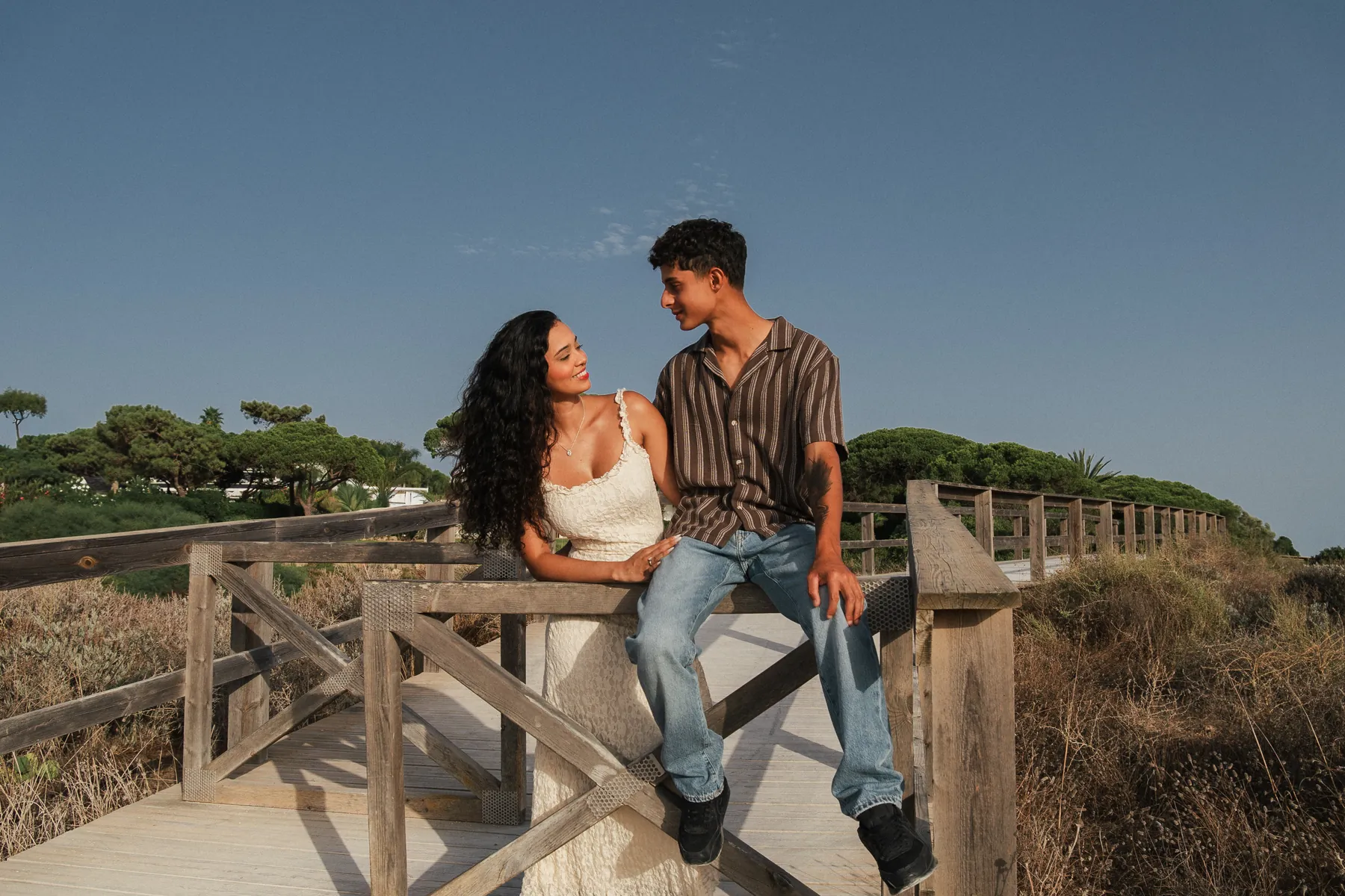 Casal sentado num passadiço de madeira sobre as dunas do Algarve
