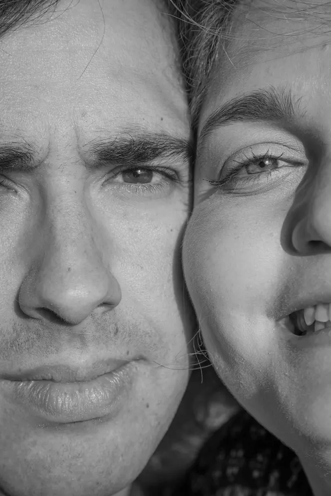 Retrato a preto e branco de dois rostos encostados, com luz lateral