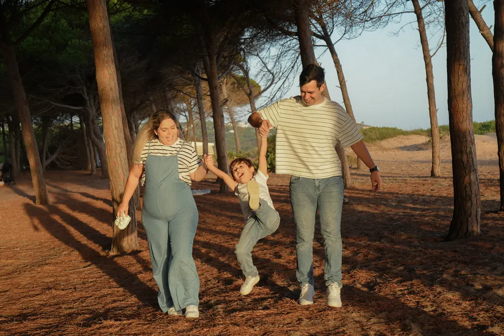 Família a caminhar e a brincar entre pinheiros ao pôr do sol no Algarve