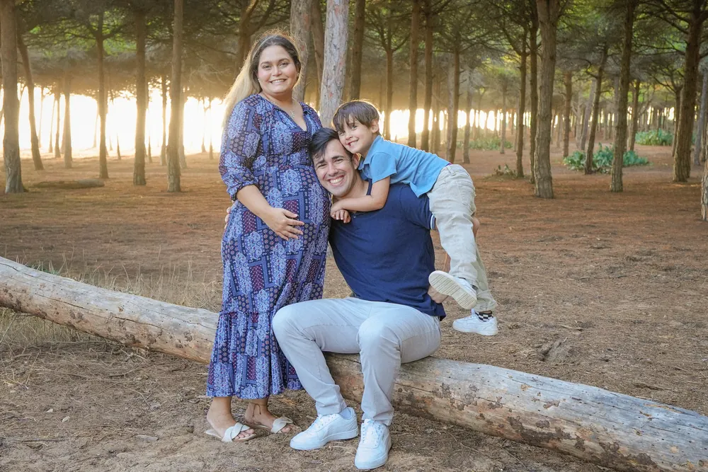Família sentada num tronco num pinhal com luz dourada a atravessar as árvores, Algarve
